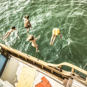 Aerial view of young people jumping from sailing boat on sea trip