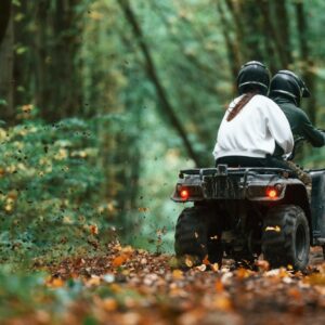 Driving on the footpath. Young couple riding a quad bike in the forest